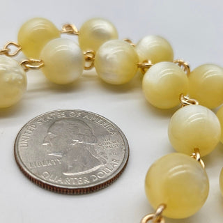 Yellow beaded bracelet next to a quarter on a white background