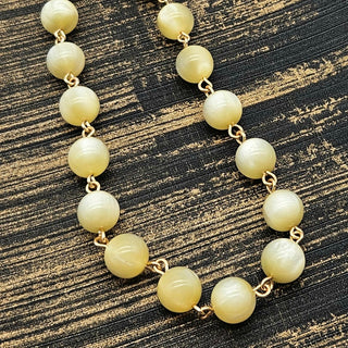 Necklace with cream-colored beads on a textured black and gold background