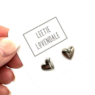 Heart-shaped silver earrings on a white card with 'Leetie Lovendale' branding.