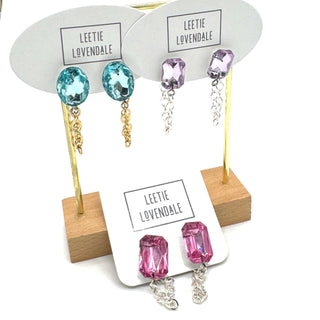 Earrings with colorful gemstones on display cards with 'Leetie Lovendale' branding.
