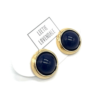 Gold-framed round earrings with dark blue centers on a white background, featuring the brand 'Leete Lovendale'.