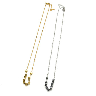 A silver and a gold necklace on a white background. It is a fine chain with several cube beads at the center.