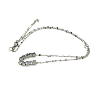A silver necklace on a white background. It is a fine chain with several cube beads at the center.