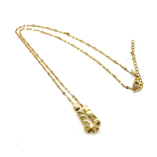 A gold necklace on a white background. It is a fine chain with several cube beads at the center.