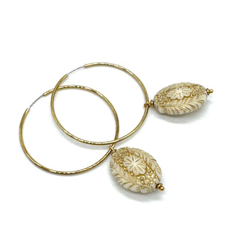 Hoop earrings with carved white bead dangles with gold leaf.