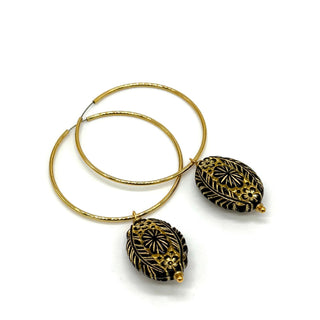 Hoop earrings with carved black bead dangles with gold leaf.