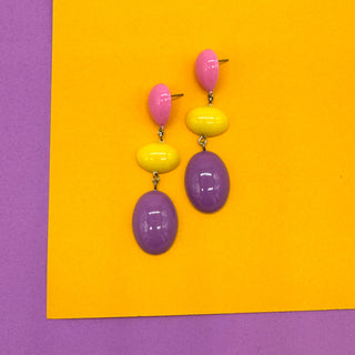Colorful earrings on a yellow and purple background