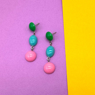Pair of earrings with green, blue, and pink beads on a purple and yellow background