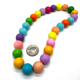 Colorful beaded necklace with a quarter for scale on a white background
