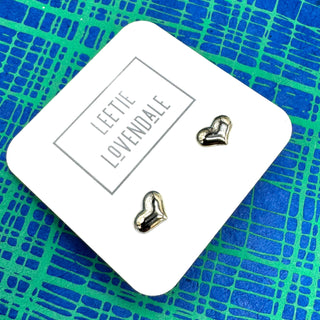 Heart-shaped earrings on a branded card with a blue and green patterned background