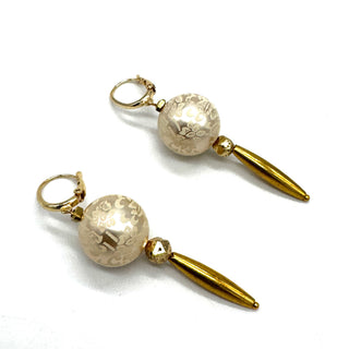 Dangle earrings with floral cream colored beads and golden accents on a white background.