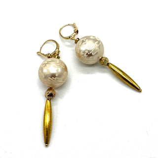 Dangle earrings with floral cream colored beads and golden accents on a white background.