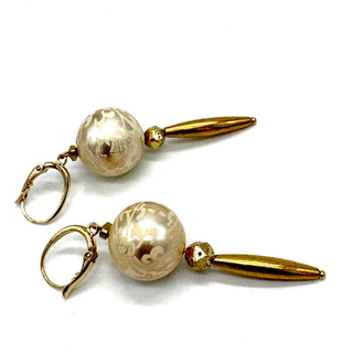 Dangle earrings with floral cream colored beads and golden accents on a white background.