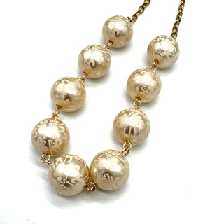 Closeup of half chain and half beaded necklace, featuring gold chain and floral etched pearl lucite beads.