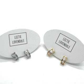 Silver and gold crystal hoop earrings on branded earring cards.