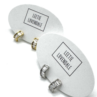 Silver and gold crystal hoop earrings on branded earring cards.