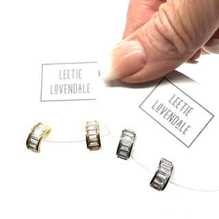 Silver and gold crystal hoop earrings on branded earring cards.