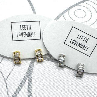 Silver and gold crystal hoop earrings on branded earring cards.