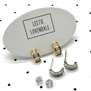 Silver and gold crystal hoop earrings on branded earring cards.