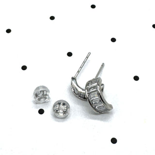 Silver and crystal hoop earrings on a polka dot background.