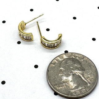 Gold and crystal hoop earrings on a polka dot background with a quarter for scale.