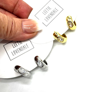 Silver and gold hoop earrings with a crystal set in the center of each.
