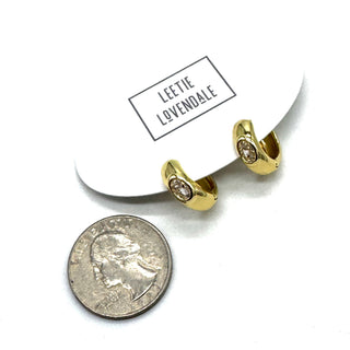 Silver and crystal hoop earrings on an earring card with a quarter for scale.