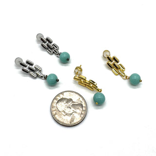 Silver and gold drop earrings with a quarter for scale.