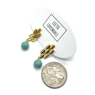 Gold drop earrings with a turquoise glass bead with a quarter for scale.