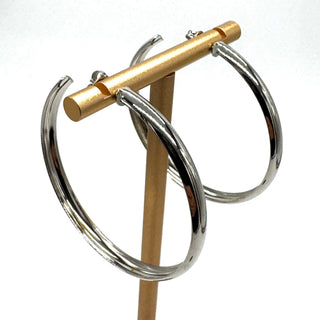 Large silver hoop earrings on a gold stand.