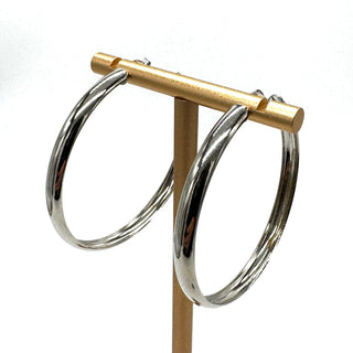 Large silver hoop earrings on a gold stand.
