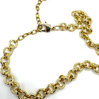 A close-up of a gold chain necklace with a lobster clasp, arranged in a loose loop on a plain white background.