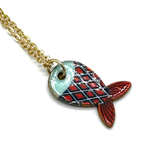 A gold chain necklace with a fish-shaped pendant featuring a red and navy blue plaid pattern on one side and a light blue enamel section on the other, shown on a plain white background.