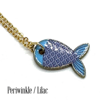 A gold chain necklace with a fish-shaped pendant featuring blue and lilac enamel scales, shown on a white background with the text 'Periwinkle / Lilac' at the bottom.