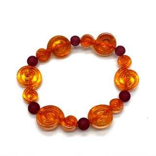 A beaded stretch bracelet featuring translucent amber spiral beads and matte dark red round beads, displayed on a clean white background.