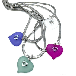 Four heart-shaped pendant necklaces with silver snake chains on a plain white background.