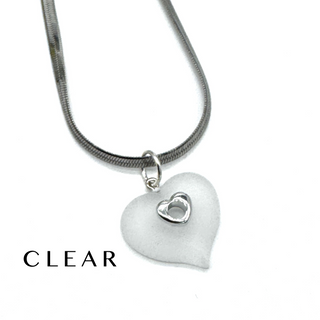 A silver snake chain necklace with a frosted clear heart-shaped pendant featuring a small silver heart in the center, shown on a white background with the word 'CLEAR' printed in the lower left.
