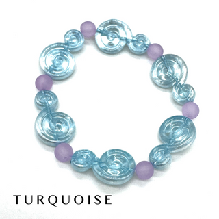 A beaded stretch bracelet featuring translucent light blue spiral beads and matte lavender purple round beads, displayed on a clean white background with the word 'TURQUOISE' printed below.