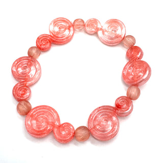 A beaded stretch bracelet featuring translucent pink spiral beads and smooth, round dusty pink beads, displayed on a clean white background.