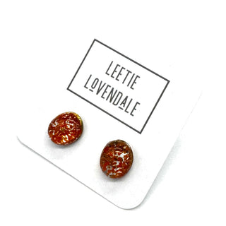 A pair of oval stud earrings with a marbled orange pattern, displayed on a white card printed with the brand name 'LEETIE LOVENDALE'.