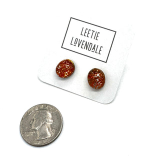 A pair of oval orange stud earrings on a white display card labeled 'LEETIE LOVENDALE,' with a U.S.