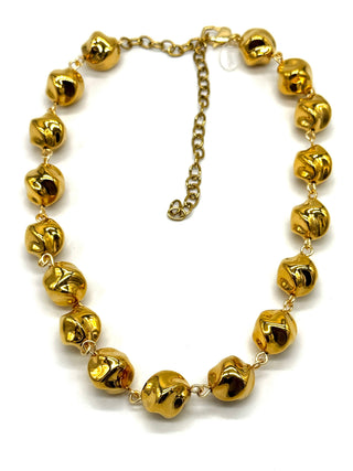 A gold-tone necklace featuring multiple small, shiny metallic beads linked by delicate chains, with an adjustable chain extender clasp, shown on a plain white background.