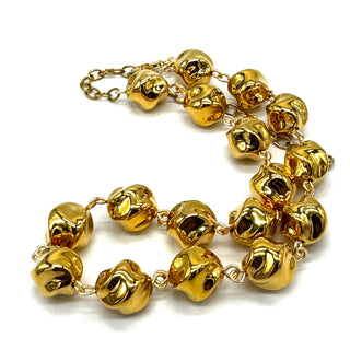 A gold-tone chain necklace featuring multiple small, shiny twisted round-shaped beads, displayed on a clean white background.