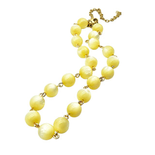 Yellow beaded necklace with gold chain on a white background