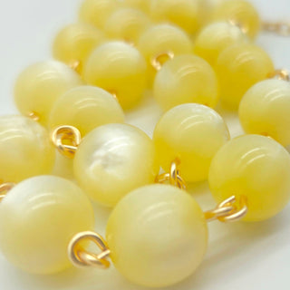 Close-up of a yellow beaded necklace with gold clasps on a white background