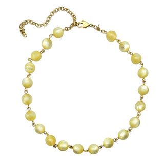 Cream colored moonglow beaded necklace with gold chain on a white background